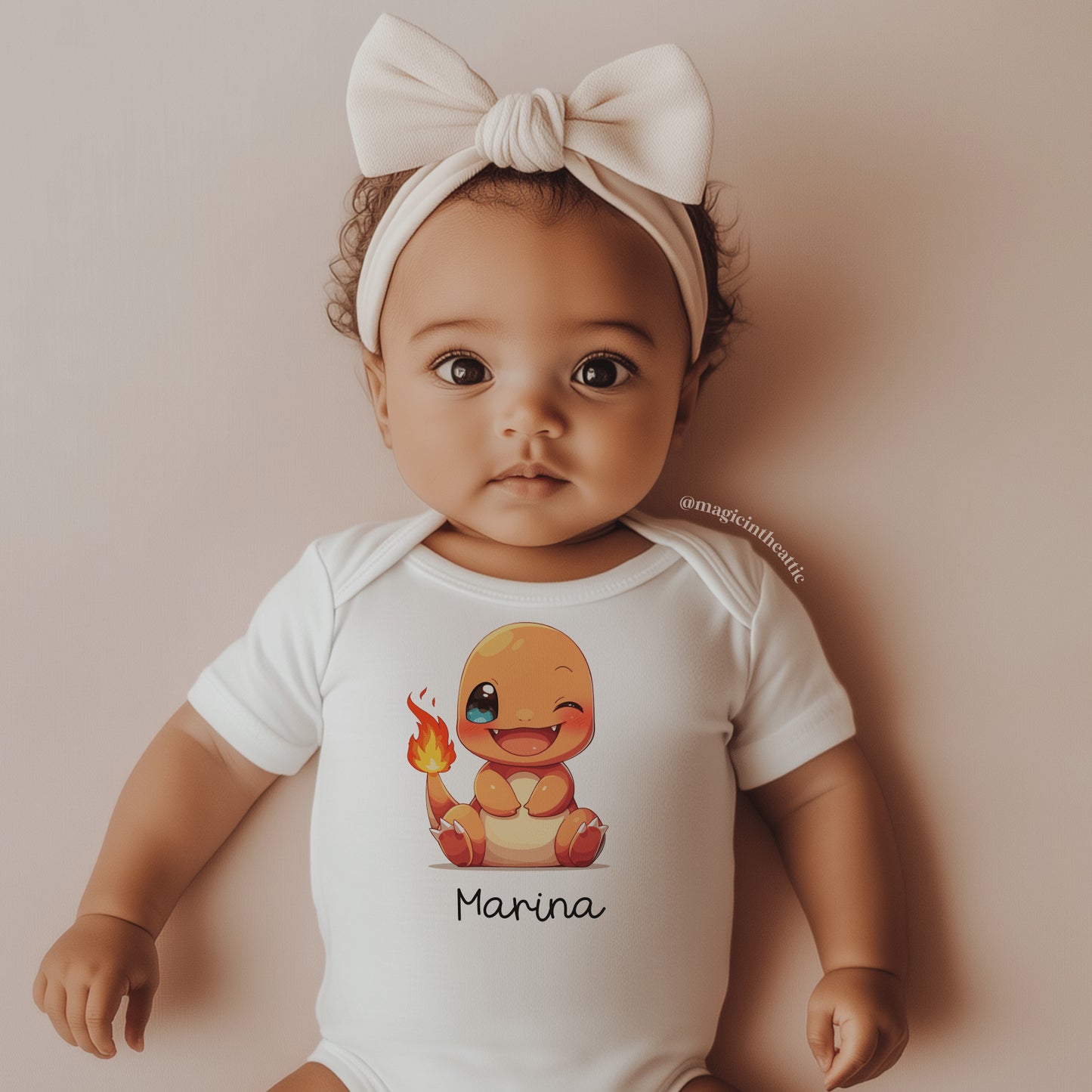 Bebé vistiendo body de charmander, diseño inspirado en pokémon. Personalizable con el nombre del bebé