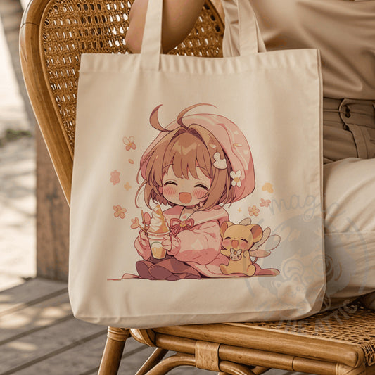 Tote bag de algodón color crudo con ilustración estilo chibi de Sakura Kinomoto de Sakura Cazadora de Cartas comiendo un helado junto a Kero, en tonos rosa y melocotón con flores, colgada en una silla de mimbre.