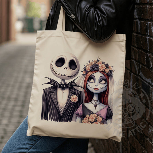 Tote bag de algodón color crudo con ilustración de Jack Skellington con traje de rayas y Sally vestida de novia con corona de rosas y velo, de Pesadilla antes de Navidad, colgada del hombro de una persona con chaqueta de cuero negra junto a una pared de ladrillo.