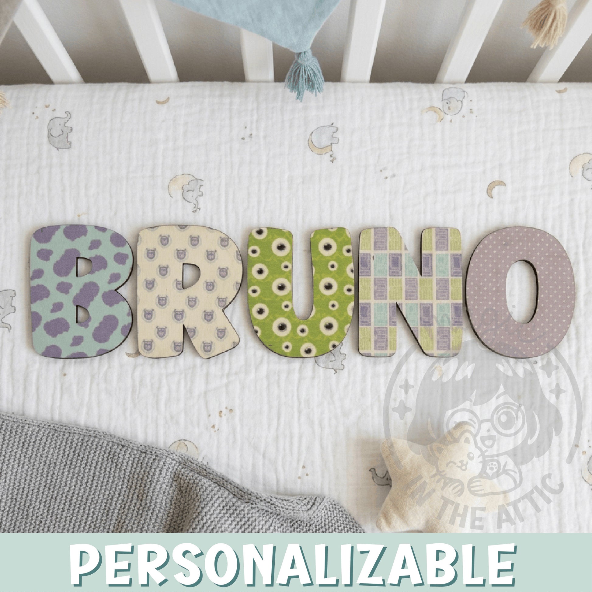 Letras decorativas de madera con estampados Monsters Inc formando el nombre BRUNO en cuna de bebé