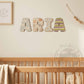 Letras de madera Toy Story ARIA apoyadas en estantería con cuna de madera al fondo