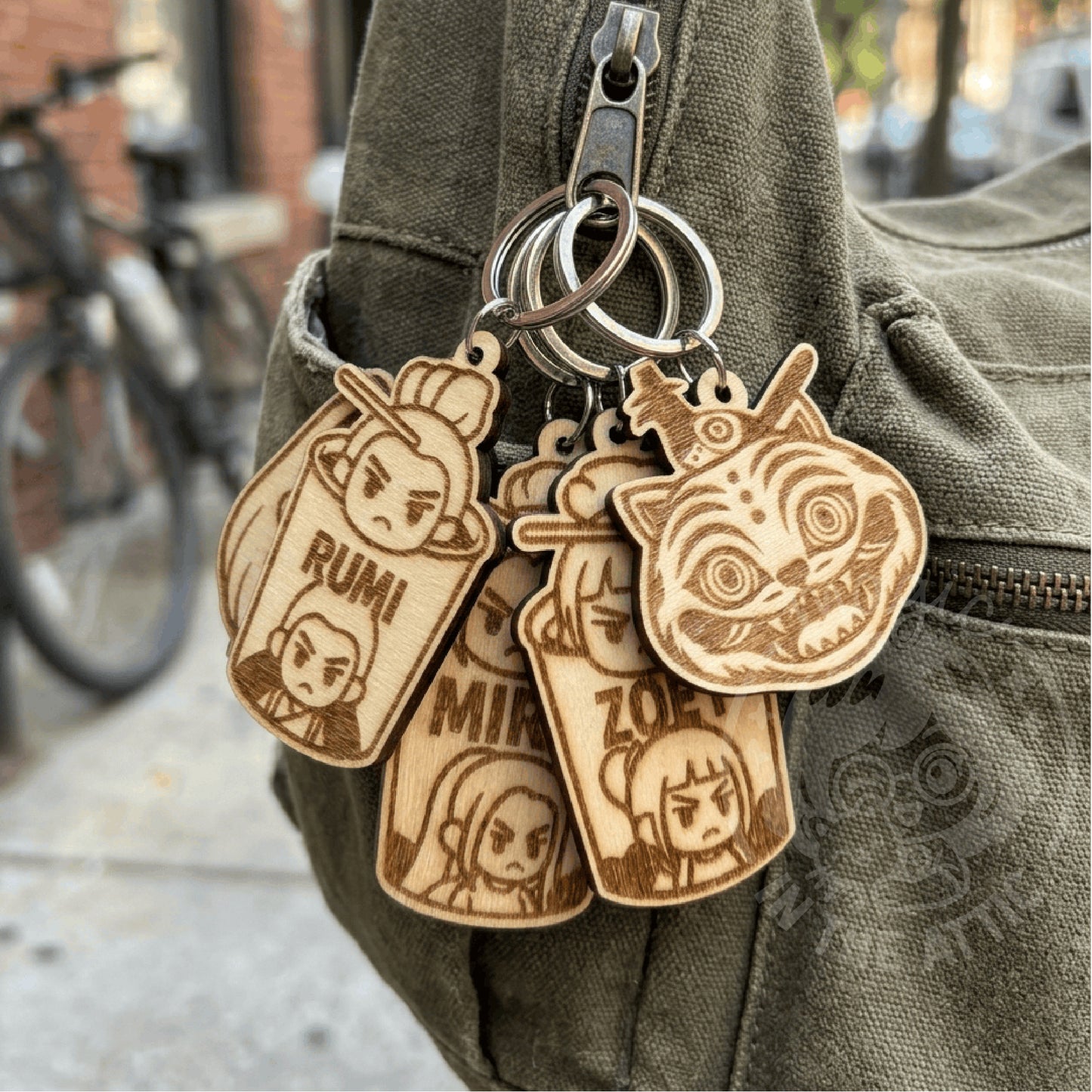 Llaveros de madera grabados de KPop Demon Hunters colgando de una mochila