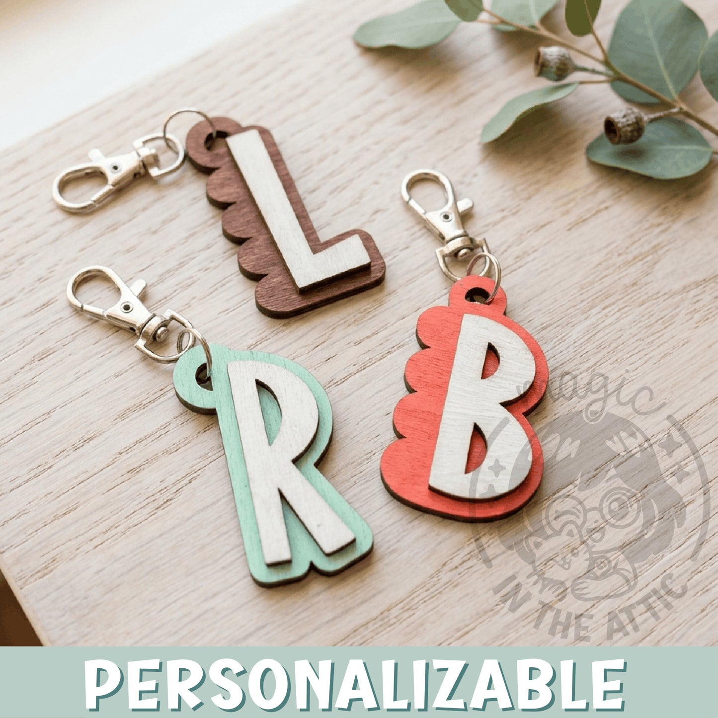 Llaveros de madera con inicial personalizada en relieve, varios colores, sobre superficie de madera clara