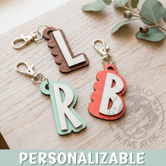 Llaveros de madera con inicial personalizada en relieve, varios colores, sobre superficie de madera clara