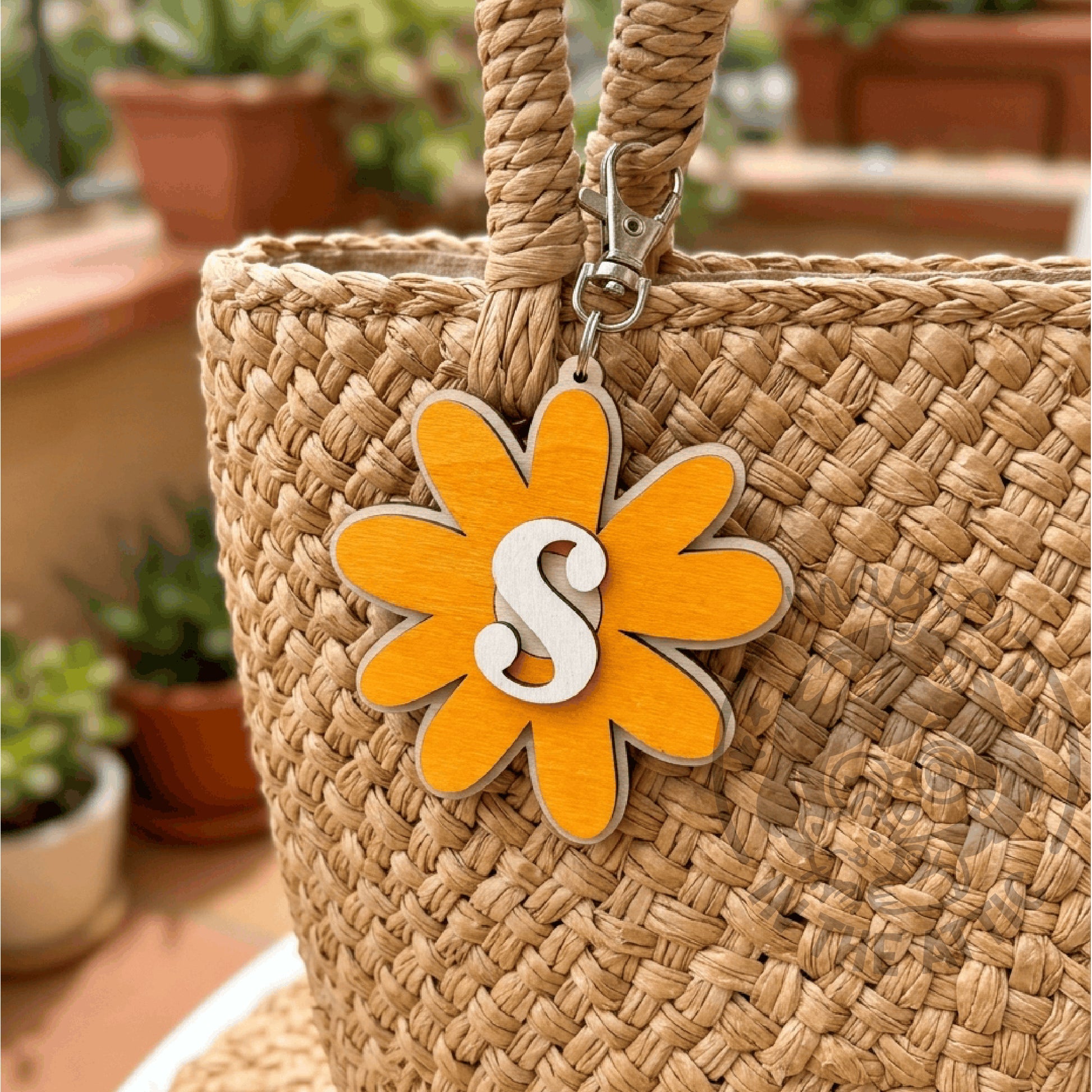 Llavero de madera flor con inicial colgado de un bolso de rafia