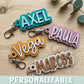 Llaveros de madera personalizados con nombre en flatlay sobre mesa de madera