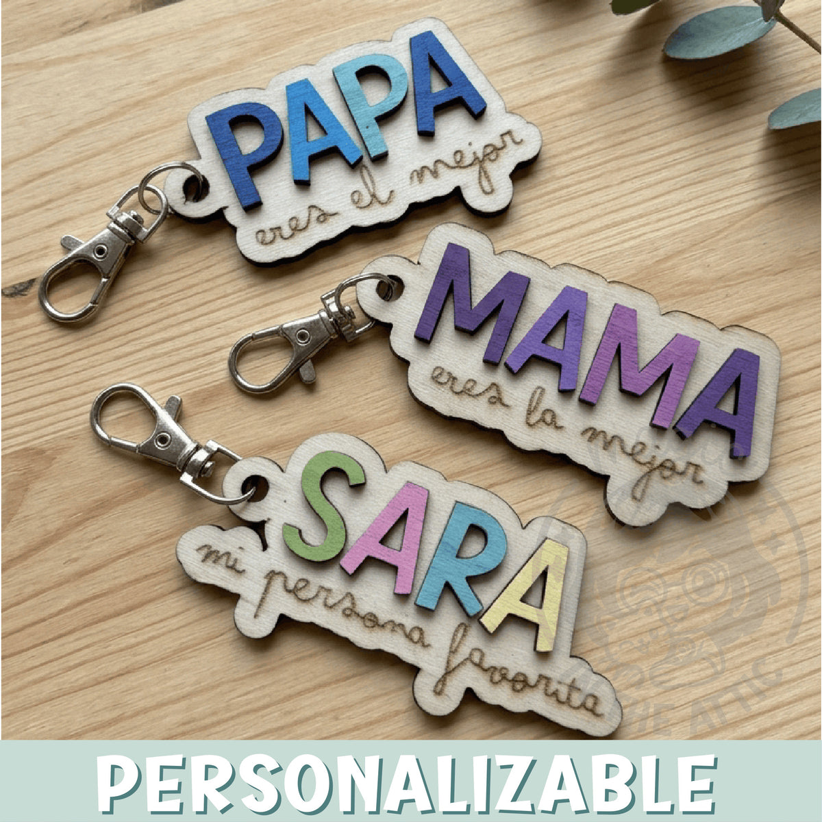 Llaveros de madera personalizados con nombre y frase Mamá y Papá eres el mejor, puestos en flatlay sobre mesa de madera