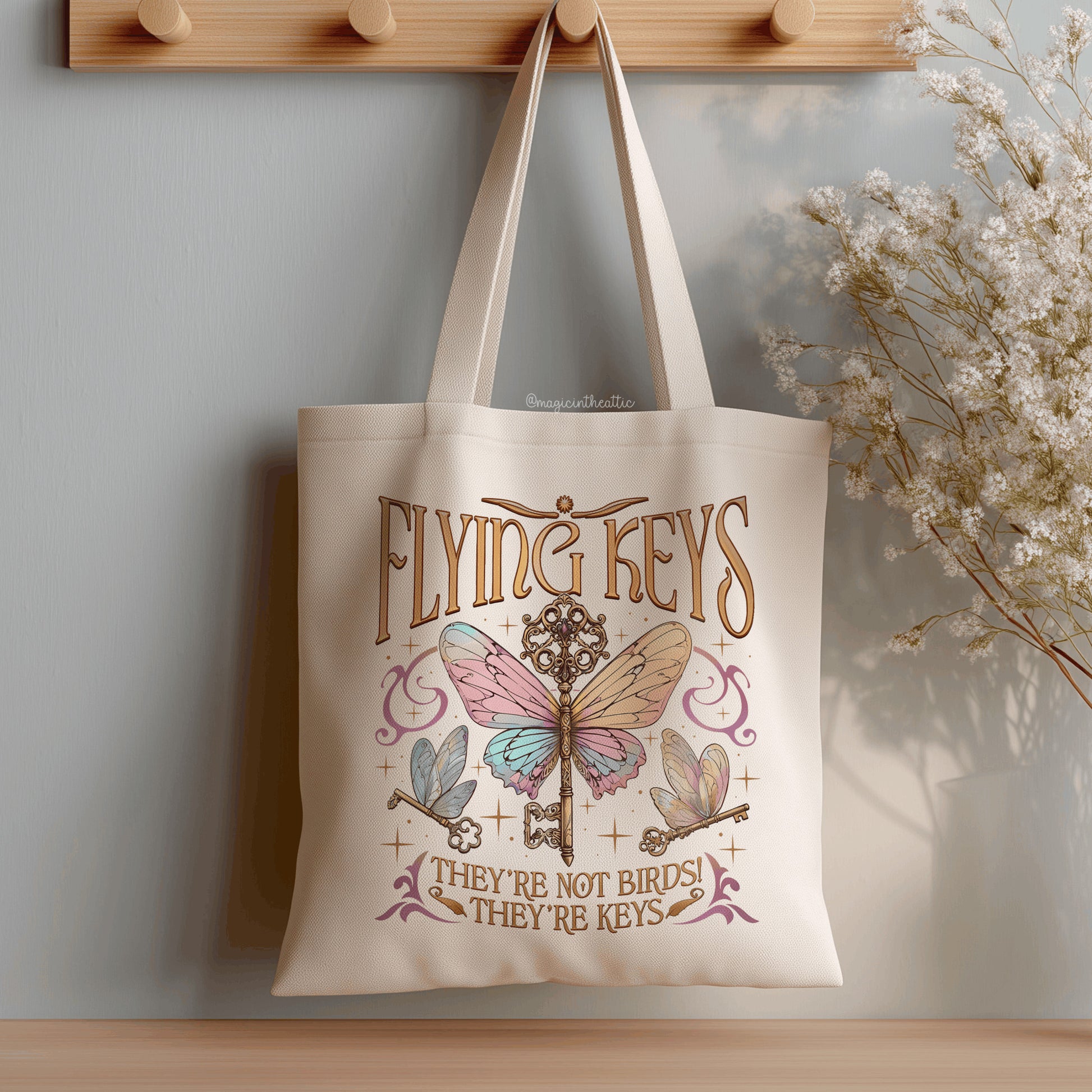 Tote bag de algodón natural con diseño Flying Keys Harry Potter llaves con alas y texto They're Not Birds They're Keys, colgada en perchero de madera